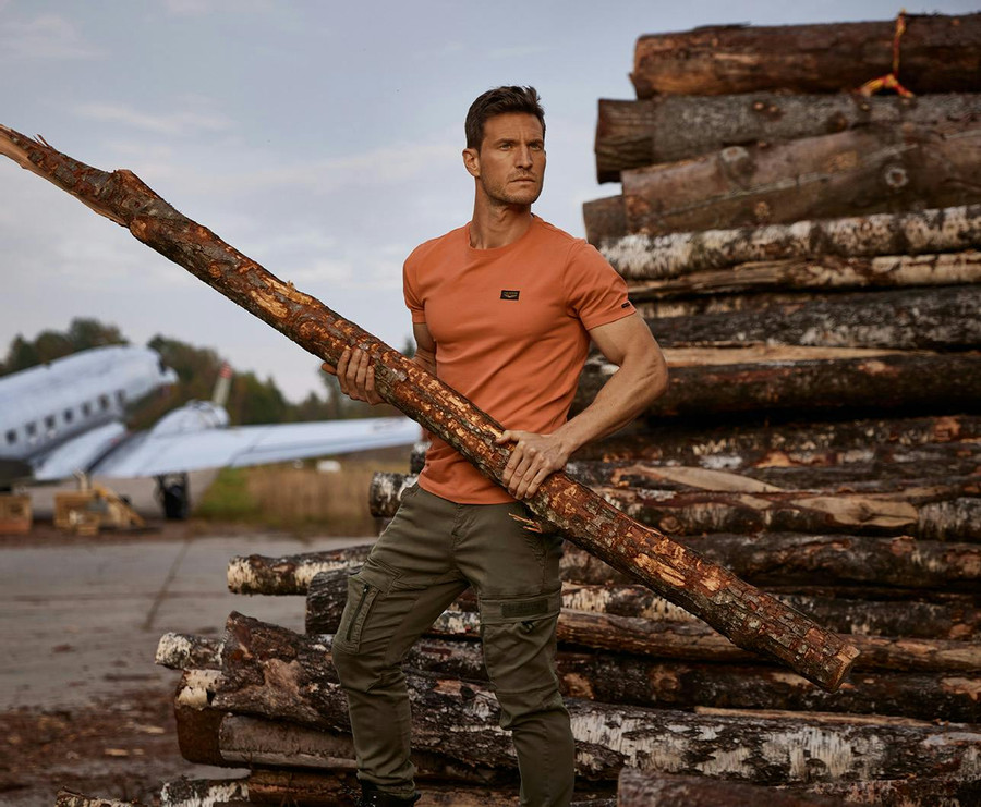 Mann mit orangefarbenem PME Legend T-Shirt und grüner Cargohose